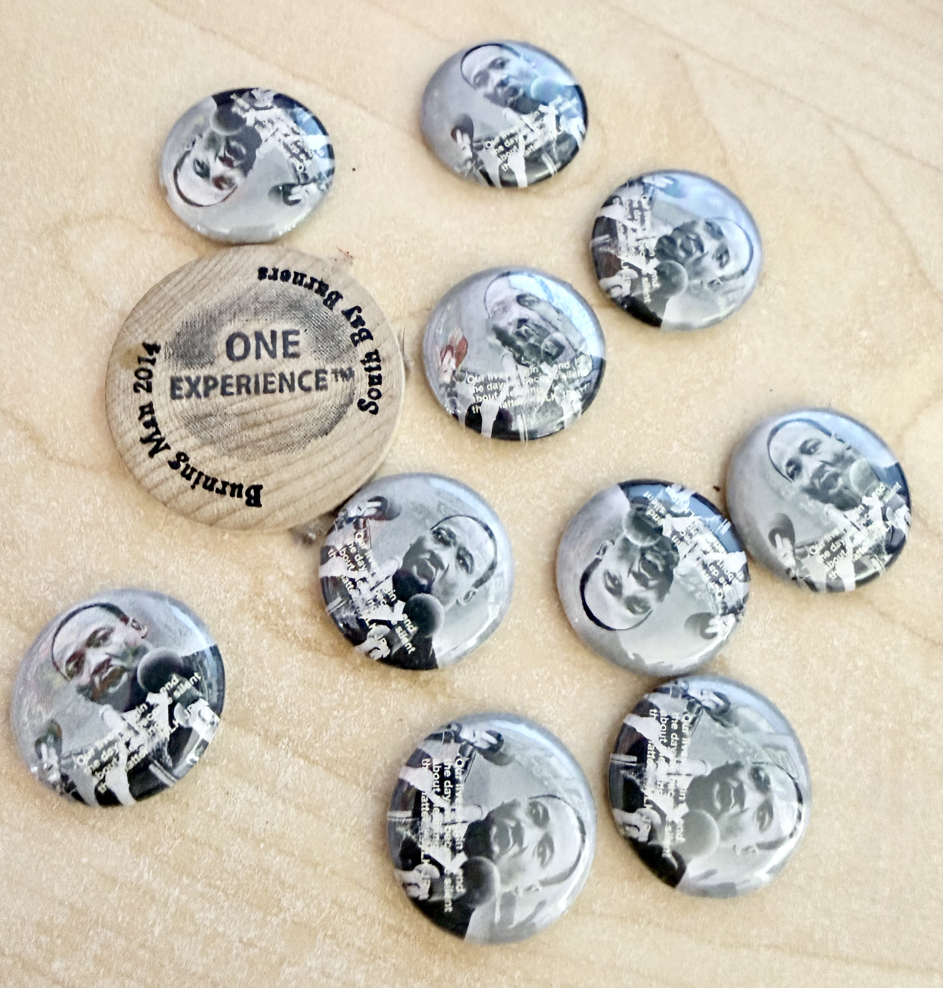 Black-and-white Martin Luther King Jr. quote buttons on a wooden surface, next to a “ONE EXPERIENCE” button.